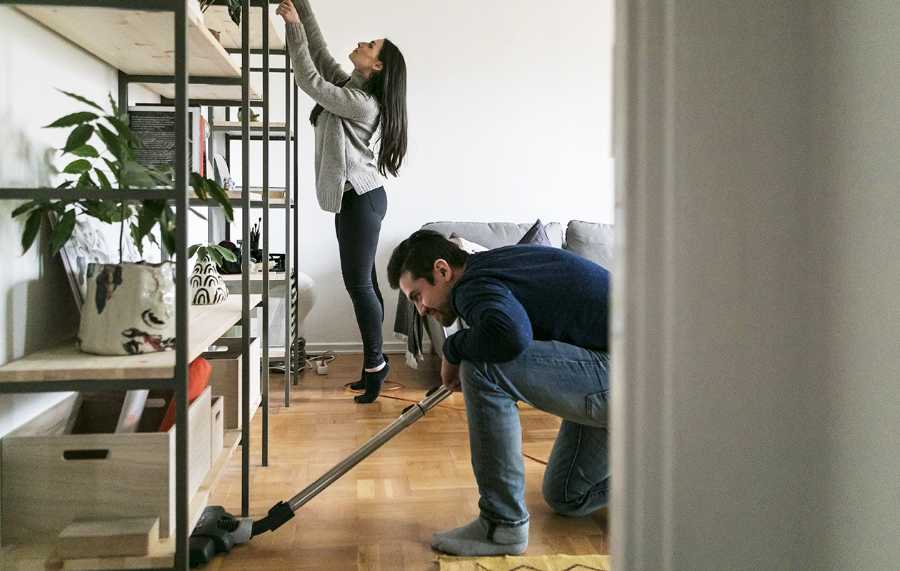 une femme fait du tri pendant qu'un homme passe l'aspirateur