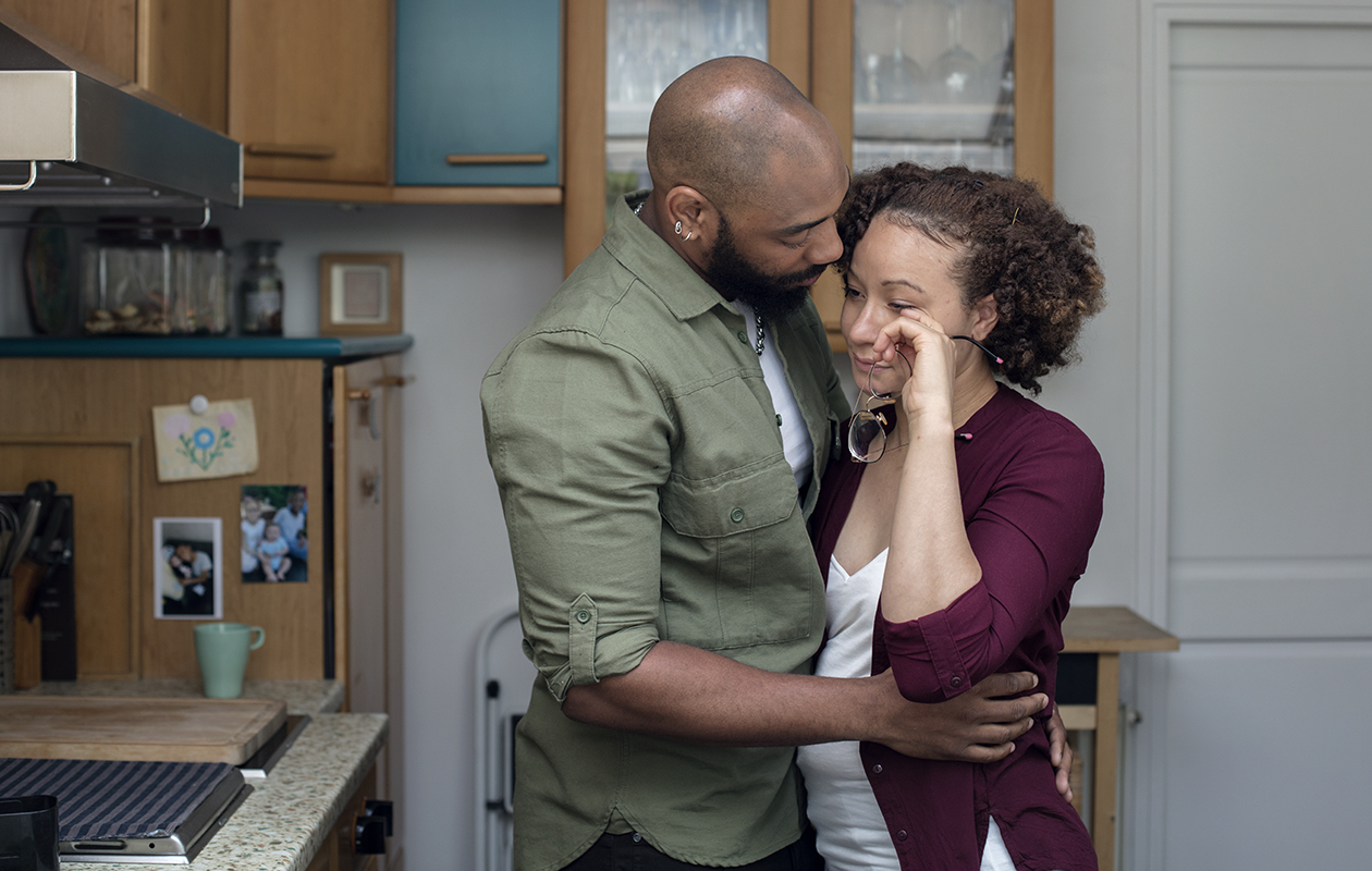 Une jeune maman pleure dans les bras de son compagnon