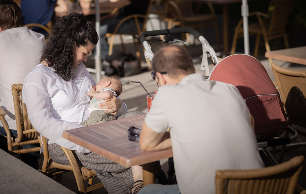 une mère en train d'allaiter à la terrasse d'un café