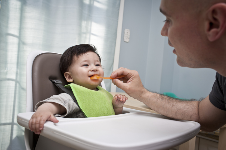 Bébé nourri par un parent (purée de légume ou fruit).