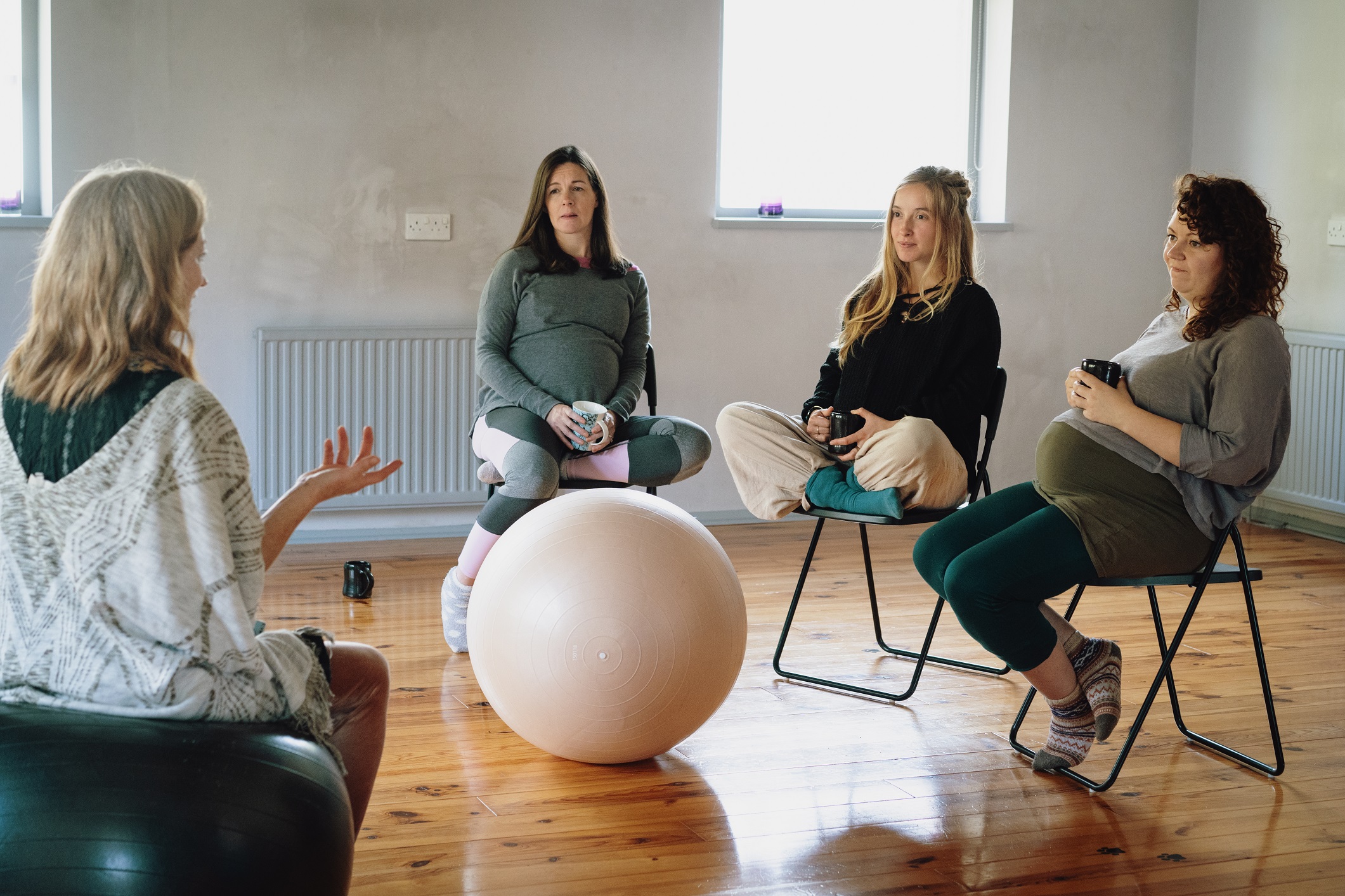 trois femmes enceintes discutent avec une professionnelle autour d'un gros ballon