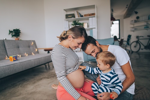 une femme enceinte, un homme et un enfant d'environ 2 ans sont en interaction