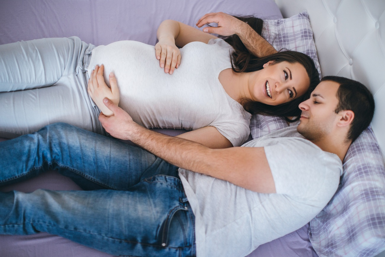 un moment de tendresse entre une femme enceinte et son compagnon, allongés