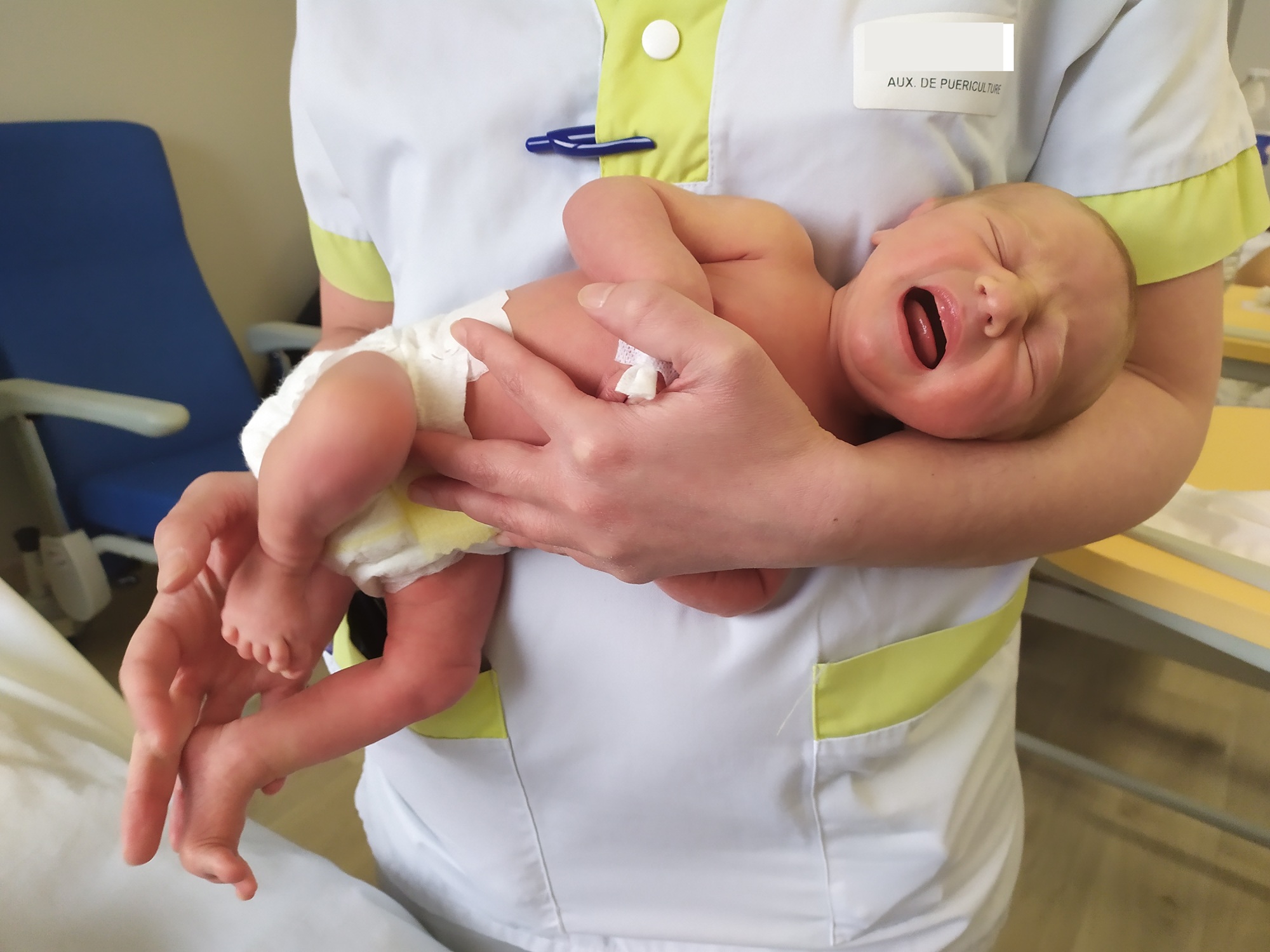 un bébé placé sur l'avant bras d'une auxiliaire de puériculture