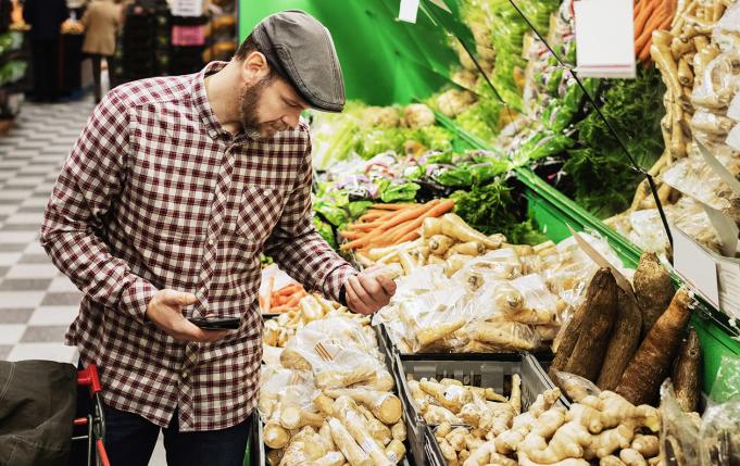 un homme au marché devant un étal de légumes racines