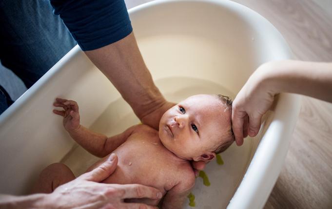 un adulte fait prendre un bain à un nouveau-né