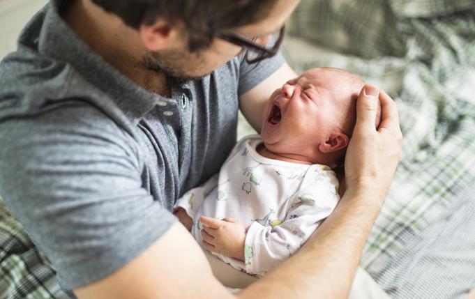 un bébé pleure très fort dans les bras d'un homme