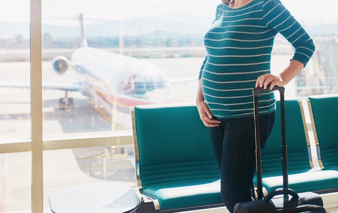 une femme enceinte à l'aéroport avec une valise