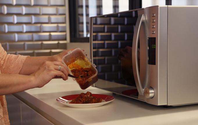 le contenu d'un récipient en plastique est transvasé dans une assiette avant de le chauffer au micro-ondes