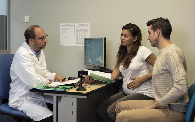 un couple dont la femme est enceinte parle à un professionnel de santé dans son cabinet