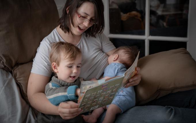 Maman allaitant en faisant la lecture à son ainé en même temps
