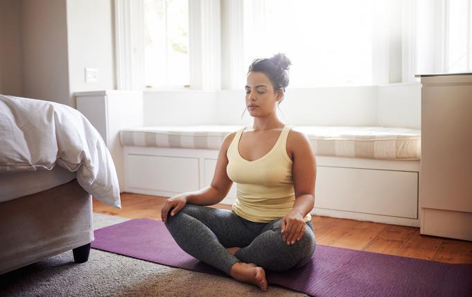 une femme médite en position du lotus dans sa chambre