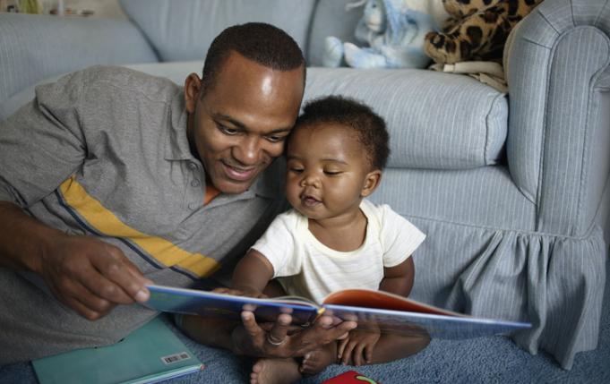Un papa en train de lire une histoire à un tout petit.