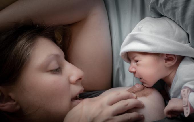 maman allongée s'apprêtant à donner le sein à un nourrisson