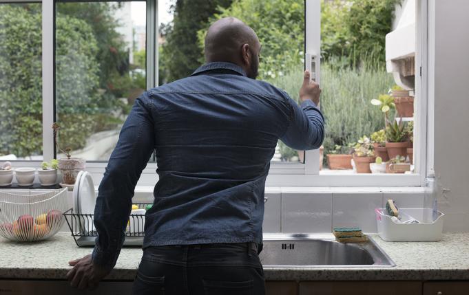 un homme ouvre la fenêtre de sa cuisine