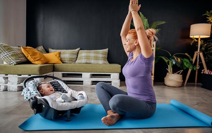 Une femme fait du yoga dans son salon avec son enfant a côté
