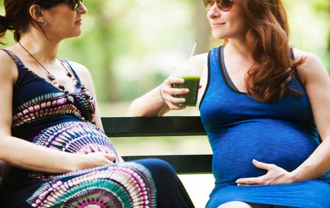 deux femmes enceinte sur un banc dont une boit un jus vert