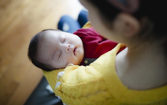 un nourrisson apaisé qui dort dans les bras d'une femme