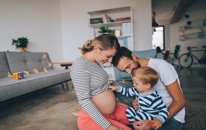 une femme enceinte, un homme et un enfant d'environ 2 ans sont en interaction