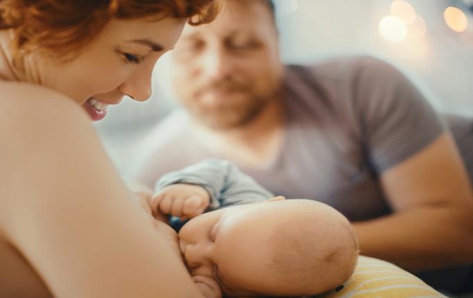 une femme allaite son bébé sous le regard attendri du papa