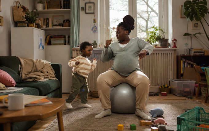 femme enceinte danse sur un ballon de grossesse à côté de son ainé