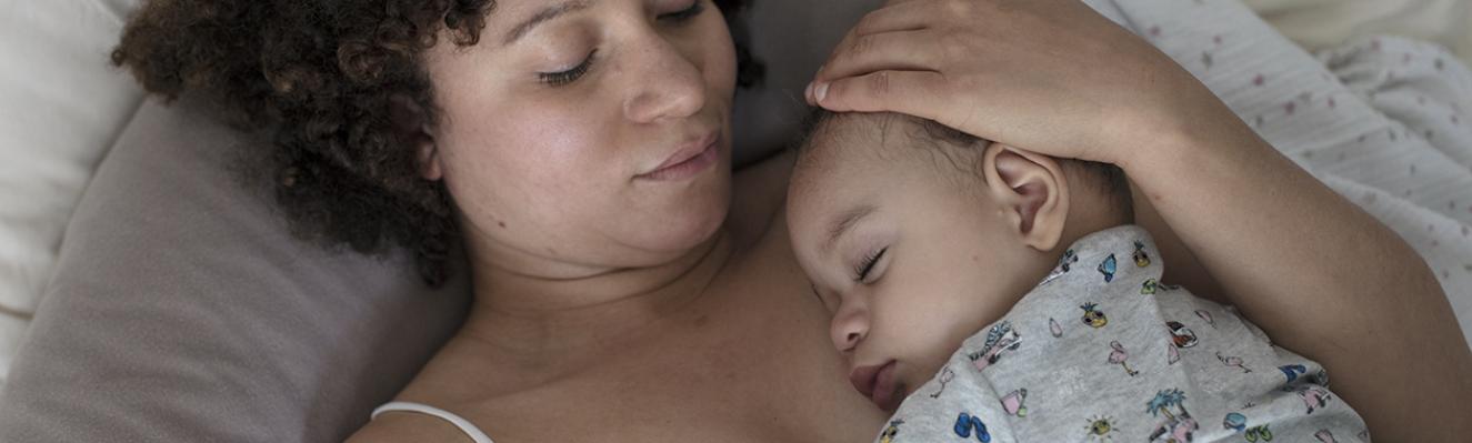 Une maman allongée, son bébé dort sur elle