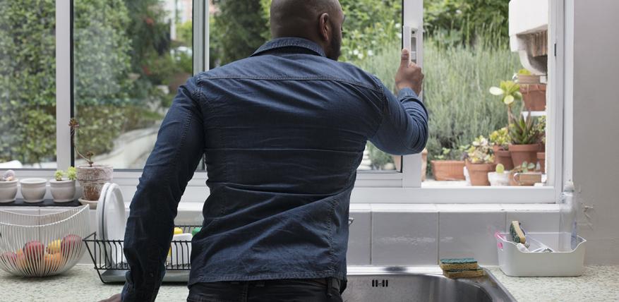 un homme ouvre la fenêtre de la cuisine