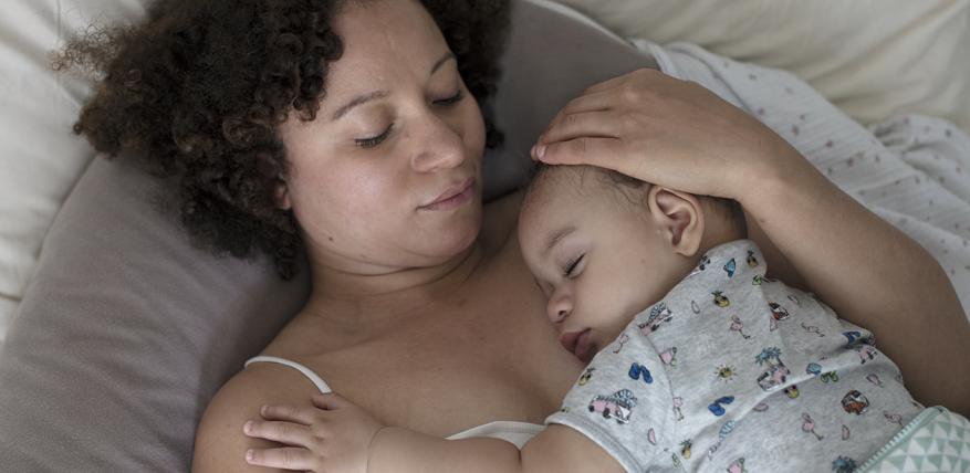 Une maman allongée, son bébé dort sur elle