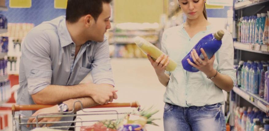 couple au supermarché qui compare deux bidons de lessive