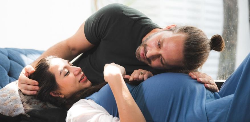 un homme écoute le ventre de sa compagne enceinte