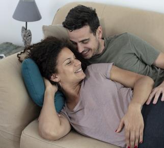 Une femme enceinte et son partenaire enlacés sur un canapé