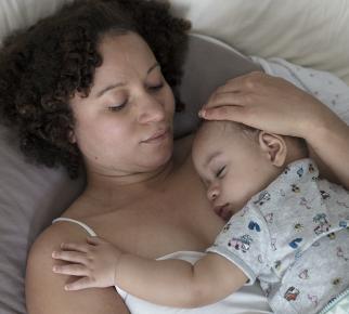 Une maman est allongée son bébé sur elle, ils nouent des liens