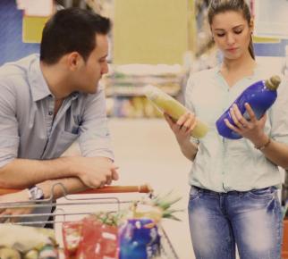 couple au supermarché qui compare deux bidons de lessive