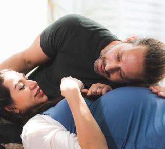 un homme écoute le ventre de sa compagne enceinte
