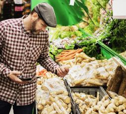 un homme au marché devant un étal de légumes racines