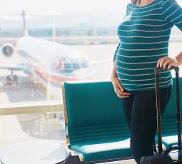 une femme enceinte à l'aéroport avec une valise