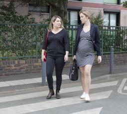 deux femmes actives dont une enceinte traversent la rue en discutant