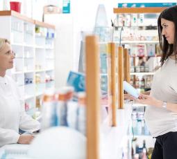 Femme enceinte au comptoir de la pharmacie regarde attentivement une boite qui lui est tendue